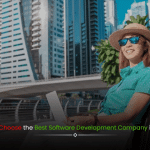 A professional woman working on a laptop, sitting at a prime location in Dubai city with iconic skyscrapers in the background, representing the best software development company in Dubai.